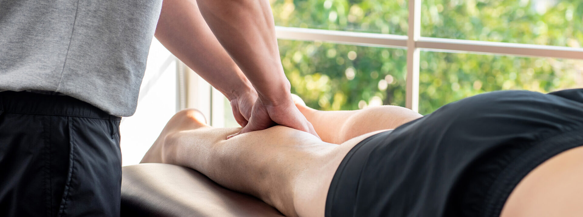 Handson Banner, Male therapist giving leg massage to athlete patient on the bed in clinic for sports physical massage therapy.